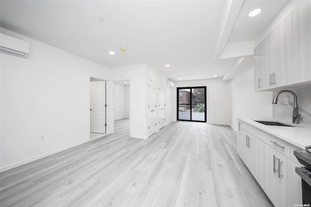 kitchen with a wall mounted AC, electric range, sink, and light hardwood / wood-style floors