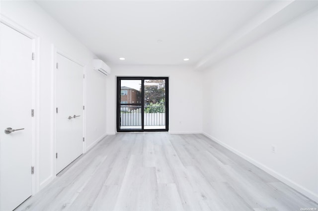 empty room featuring light hardwood / wood-style floors and a wall unit AC