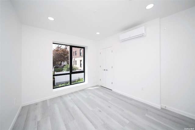 spare room featuring a wall mounted air conditioner and light wood-type flooring