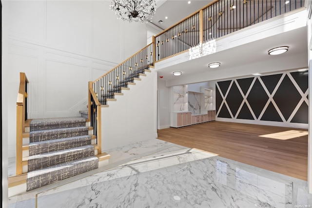 stairs featuring hardwood / wood-style floors, a high ceiling, and an inviting chandelier