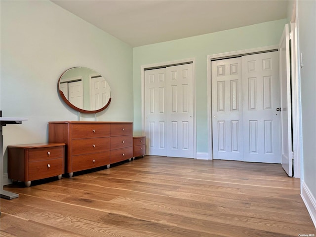 bedroom with light wood-type flooring and multiple closets