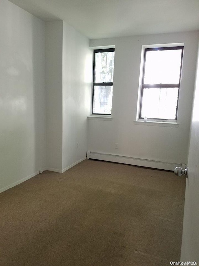 empty room featuring carpet flooring, a baseboard radiator, and a healthy amount of sunlight