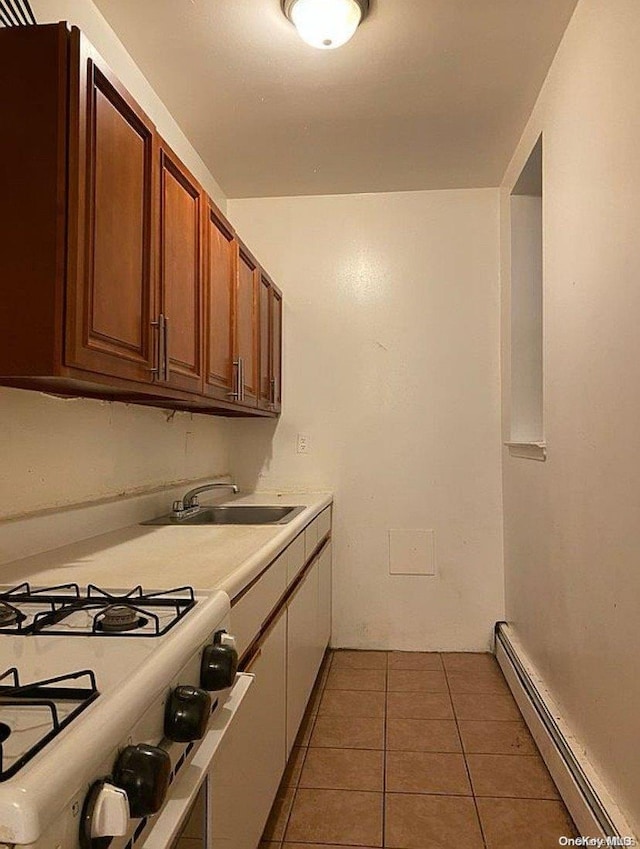 kitchen featuring white gas range, dark tile patterned floors, sink, and a baseboard radiator