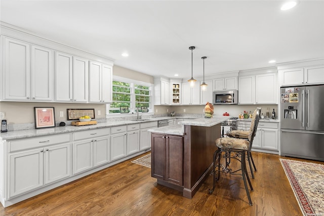 kitchen featuring pendant lighting, a kitchen island, dark wood-type flooring, and appliances with stainless steel finishes