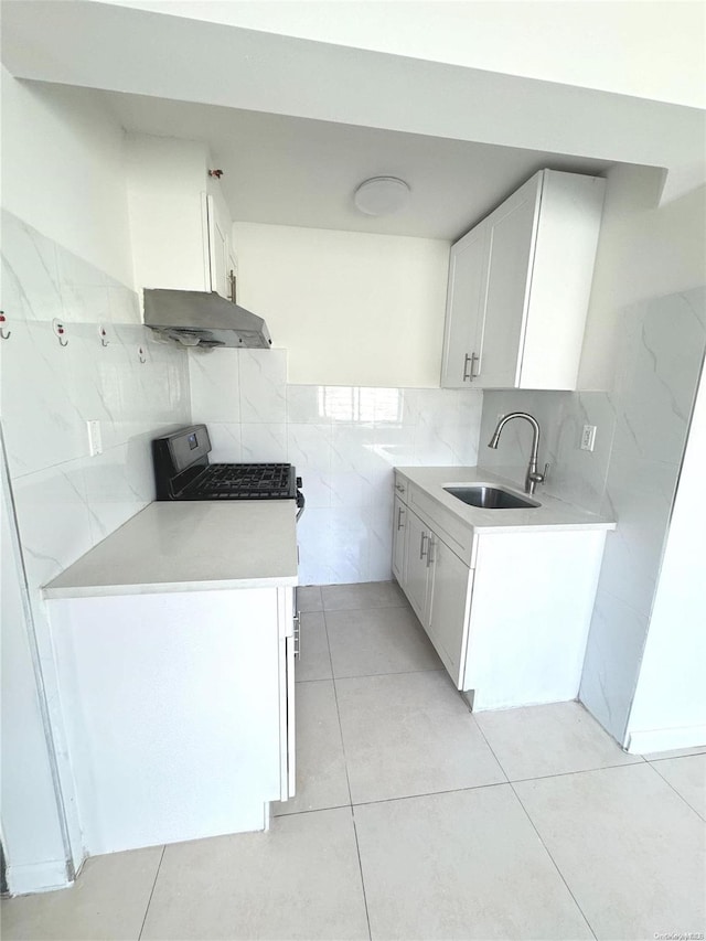 kitchen featuring white cabinets, sink, tile walls, light tile patterned flooring, and range