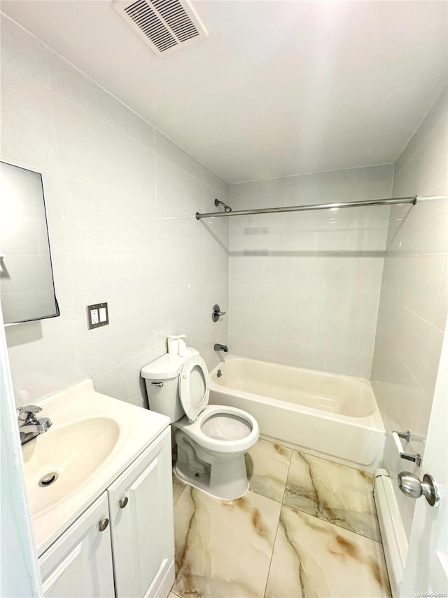 full bathroom featuring tile walls, vanity, tiled shower / bath combo, and toilet