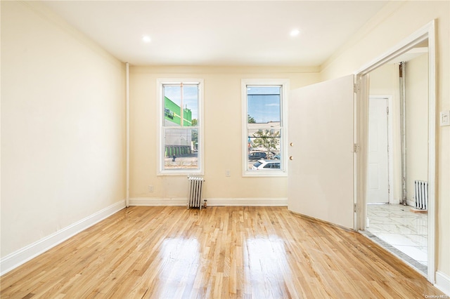 unfurnished room with light hardwood / wood-style floors, radiator, and crown molding