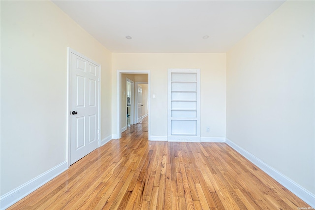 spare room featuring light wood-type flooring and built in features