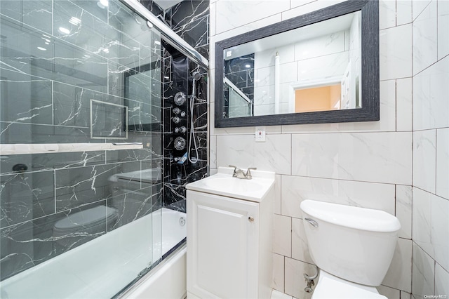 full bathroom with vanity, toilet, shower / bath combination with glass door, and tile walls