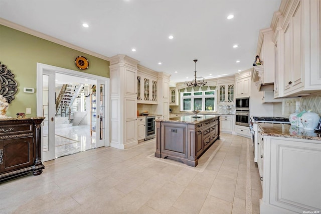 kitchen with stainless steel appliances, wine cooler, pendant lighting, decorative backsplash, and a center island with sink