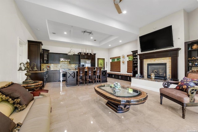 living room with ceiling fan and a tray ceiling