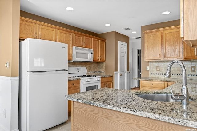 kitchen with white appliances, backsplash, light stone counters, and sink