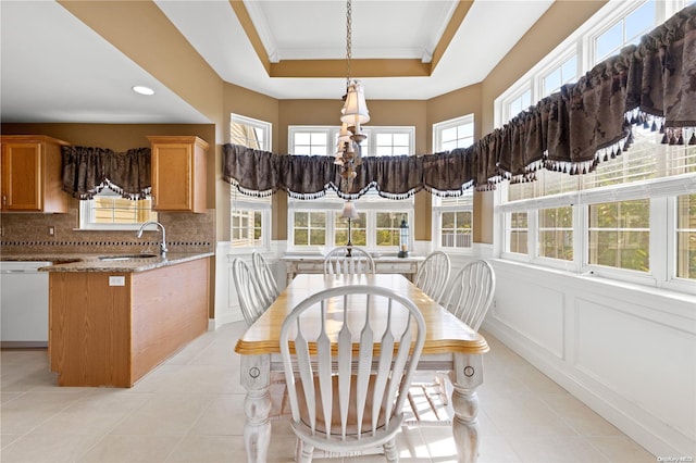 interior space with a raised ceiling, sink, and an inviting chandelier