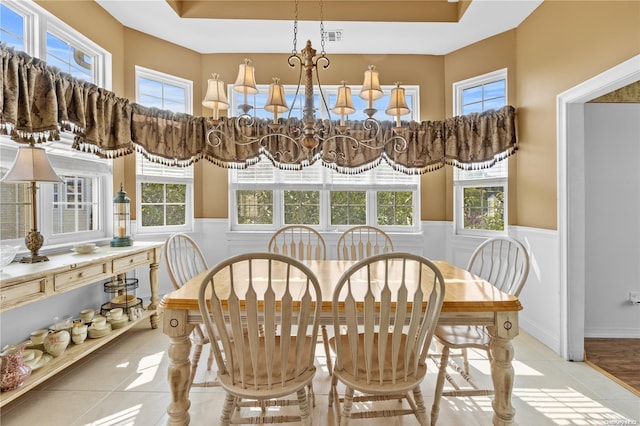 dining area featuring a raised ceiling and light tile patterned floors