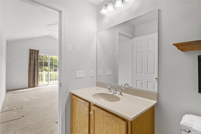 bathroom featuring vanity, toilet, and vaulted ceiling