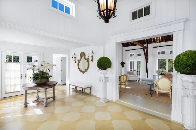 foyer with french doors, a towering ceiling, and a notable chandelier