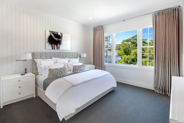 bedroom featuring dark colored carpet, wood walls, and crown molding