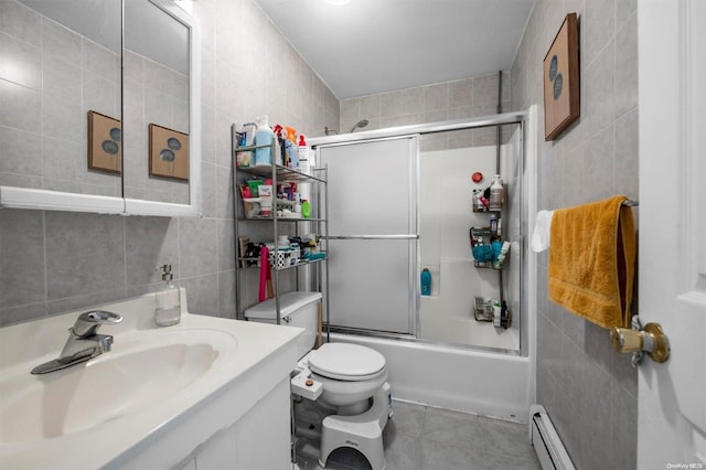 full bathroom featuring baseboard heating, enclosed tub / shower combo, toilet, vanity, and tile walls