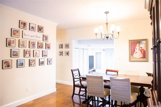 dining space featuring hardwood / wood-style floors, crown molding, and an inviting chandelier