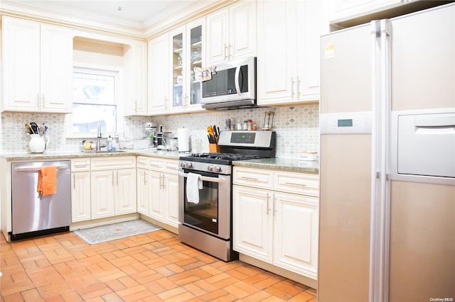 kitchen featuring light stone countertops, backsplash, stainless steel appliances, and sink