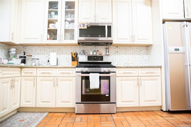 kitchen featuring decorative backsplash, stainless steel appliances, and light stone counters