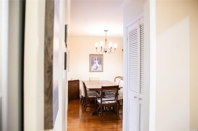 dining area featuring hardwood / wood-style floors, crown molding, and a notable chandelier