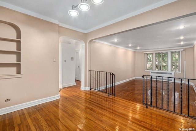 spare room with radiator heating unit, hardwood / wood-style flooring, and ornamental molding