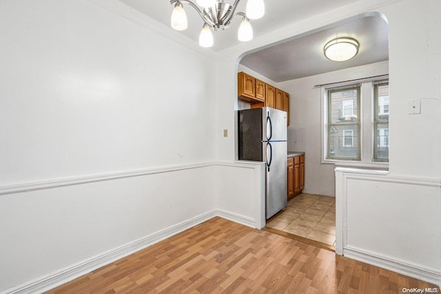 kitchen with stainless steel fridge, light hardwood / wood-style floors, crown molding, and a chandelier