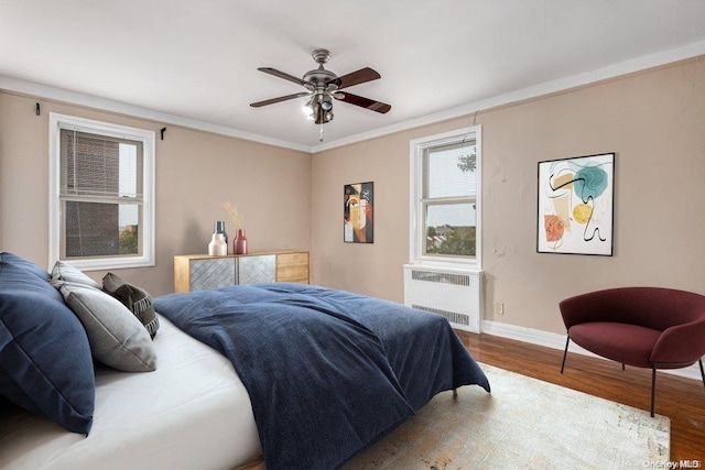 bedroom featuring radiator, ceiling fan, ornamental molding, and hardwood / wood-style flooring