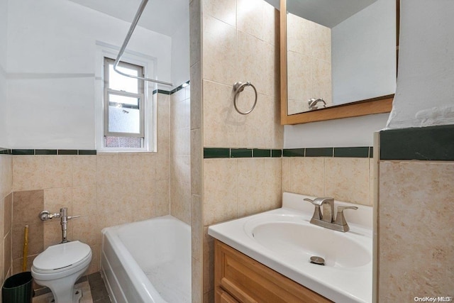 full bathroom featuring tiled shower / bath, vanity, tile walls, and toilet