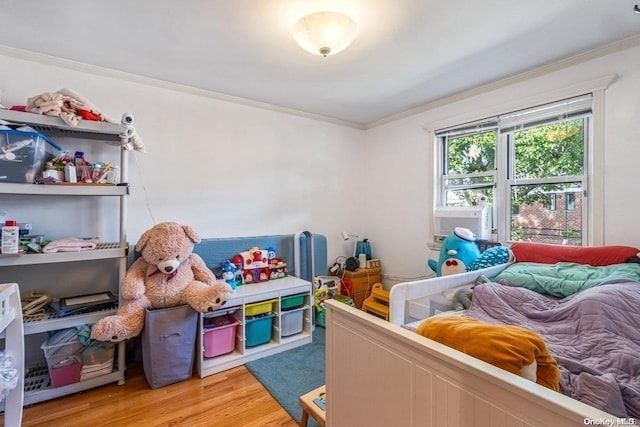 bedroom with cooling unit, ornamental molding, and hardwood / wood-style flooring