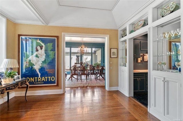 interior space with built in features, a notable chandelier, crown molding, hardwood / wood-style floors, and vaulted ceiling