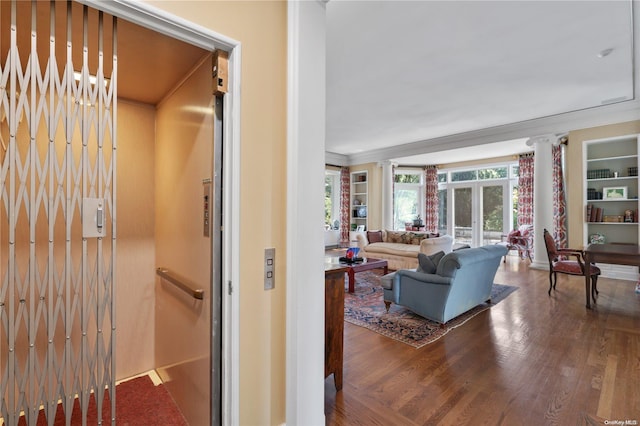 interior space with french doors, crown molding, elevator, ornate columns, and wood-type flooring