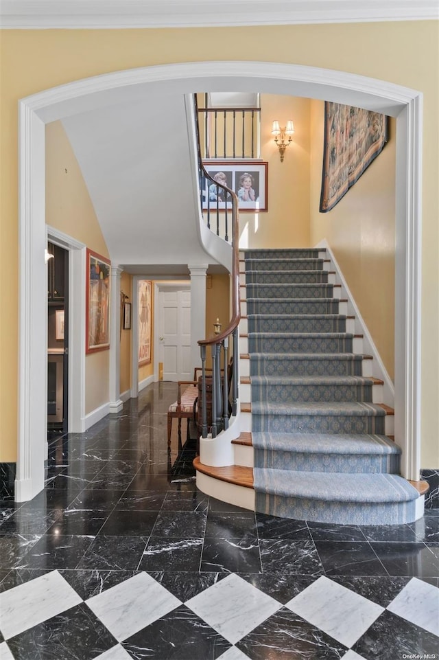 staircase with lofted ceiling, ornamental molding, and decorative columns