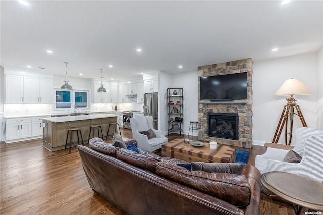 living room with hardwood / wood-style floors, a stone fireplace, and sink