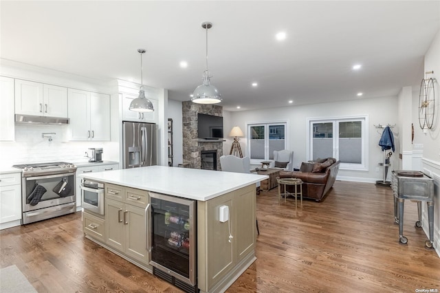 kitchen with dark wood-type flooring, beverage cooler, stainless steel appliances, a fireplace, and white cabinets