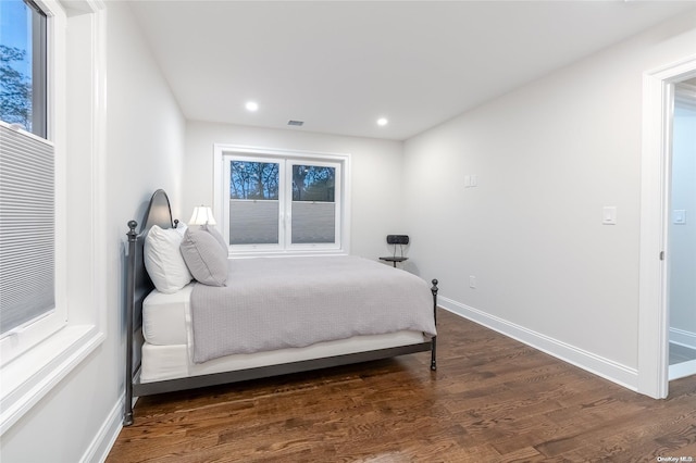 bedroom with multiple windows and dark wood-type flooring