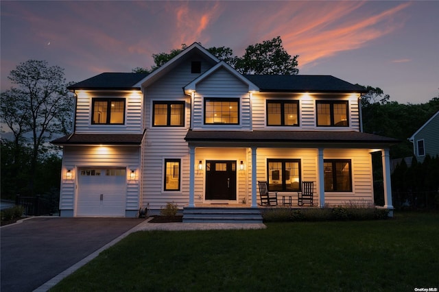 view of front of house featuring a yard, covered porch, and a garage