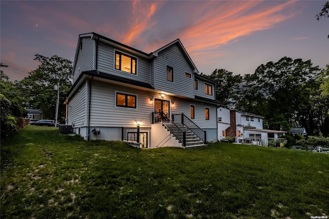 view of front of home featuring a lawn and central air condition unit