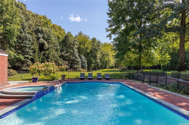 view of swimming pool with a lawn and an in ground hot tub