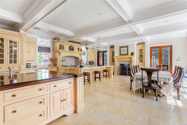 kitchen with tasteful backsplash, beamed ceiling, pendant lighting, and ornamental molding