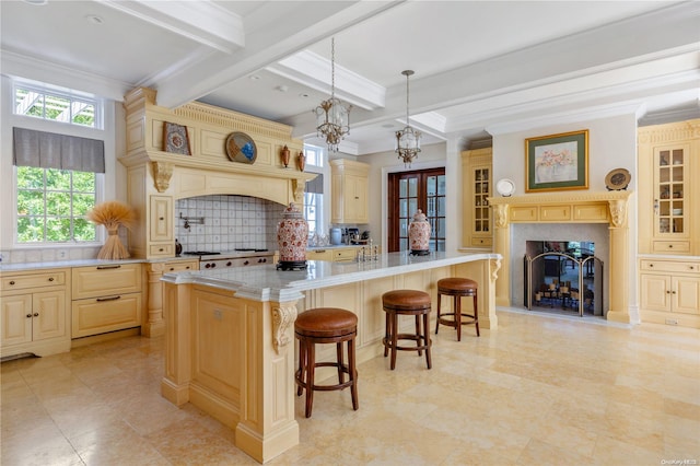 kitchen with tasteful backsplash, beamed ceiling, an island with sink, decorative light fixtures, and a kitchen bar