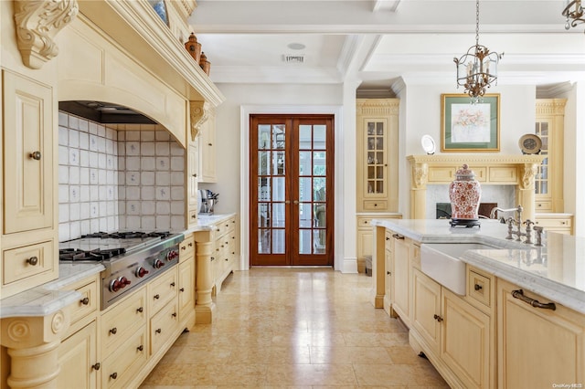 kitchen featuring french doors, stainless steel gas cooktop, sink, cream cabinetry, and hanging light fixtures