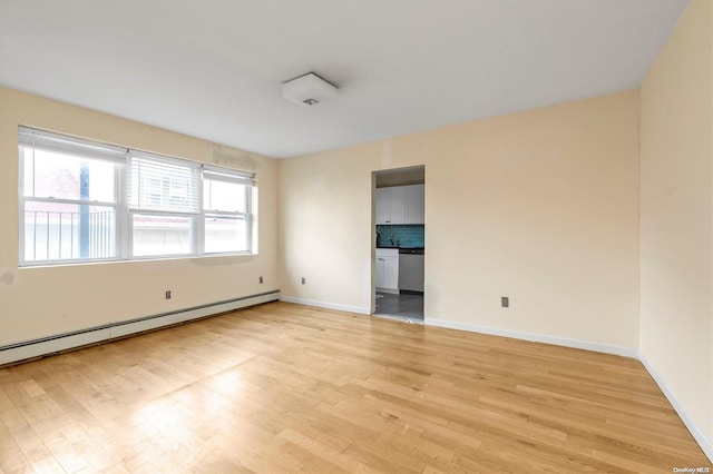 empty room featuring light hardwood / wood-style flooring and a baseboard heating unit