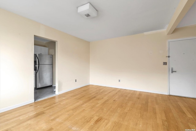 unfurnished room featuring beam ceiling and light hardwood / wood-style flooring