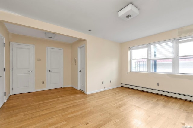 unfurnished room with light wood-type flooring and a baseboard heating unit