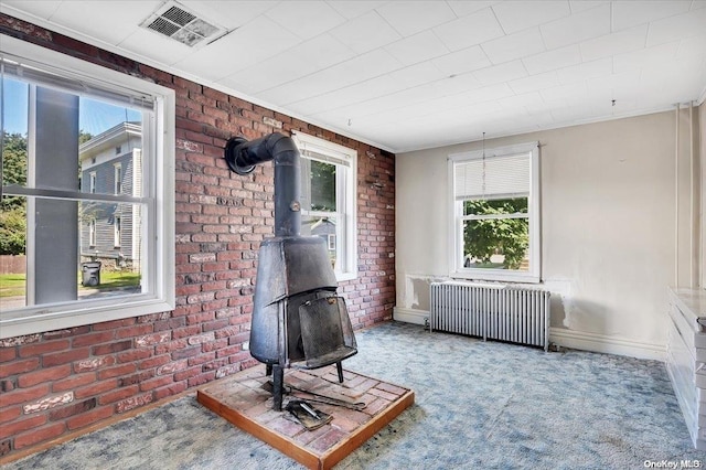 unfurnished room with radiator, a wealth of natural light, and brick wall