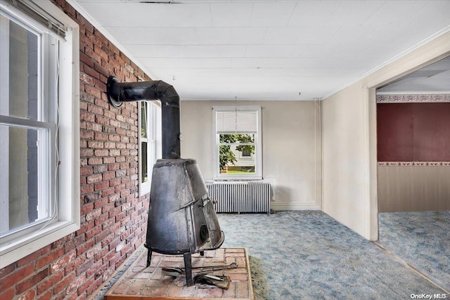 home office with carpet flooring, radiator, brick wall, and a wood stove