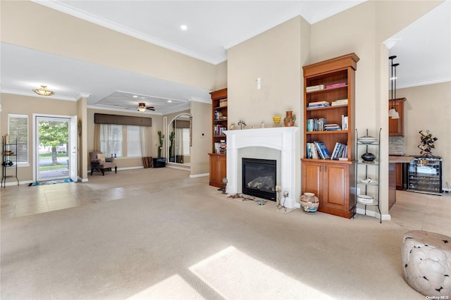 carpeted living room with ceiling fan, ornamental molding, and beverage cooler