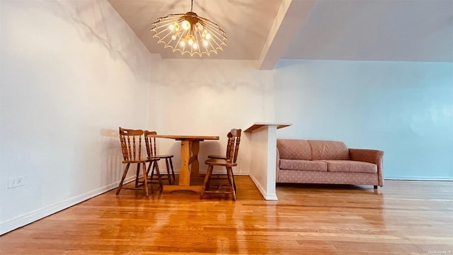 living area featuring hardwood / wood-style floors, lofted ceiling, and an inviting chandelier